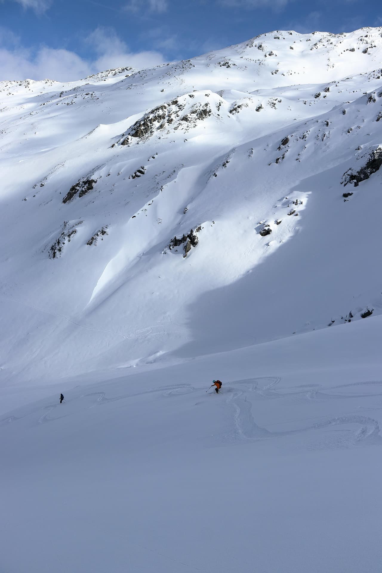 A backcountry skier descending a steep, exposed avalanche-prone couloir